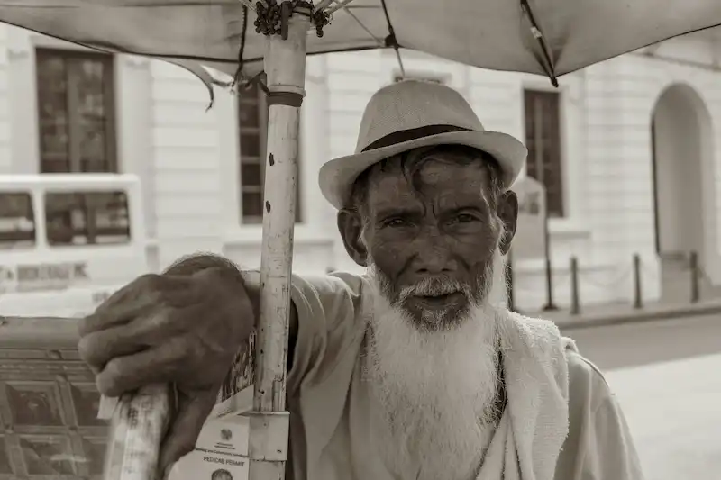 persona de avanzada edad, debajo de una sombrilla en blanco y negro